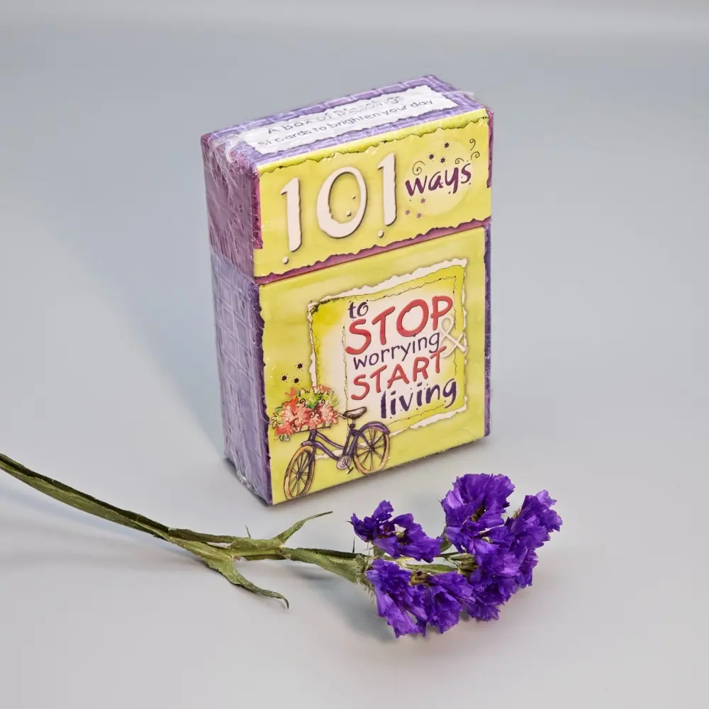 "Box of '101 Ways to Stop Worrying' inspirational cards on a light gray background."